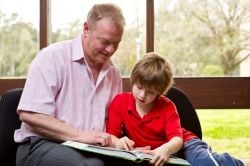 male helping young male child with reading