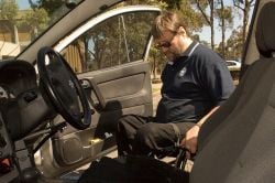 man in wheelchair entering car to drive