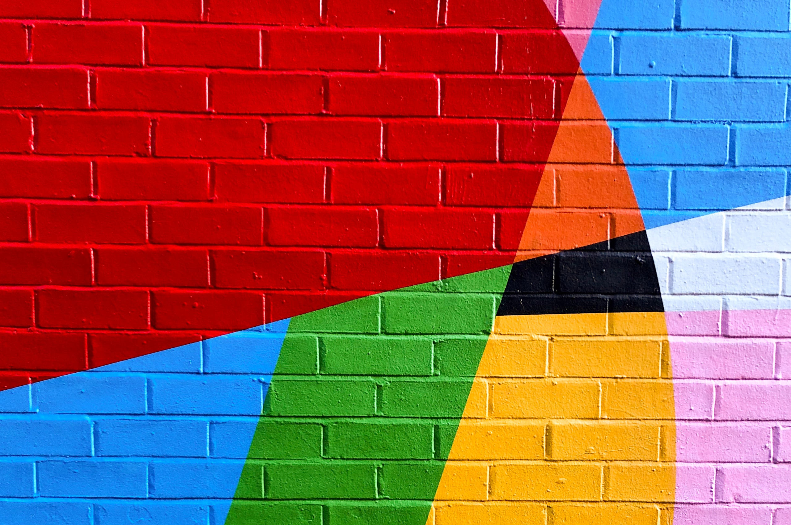 Brick wall painted with a colourful mural of bright geometric shapes
