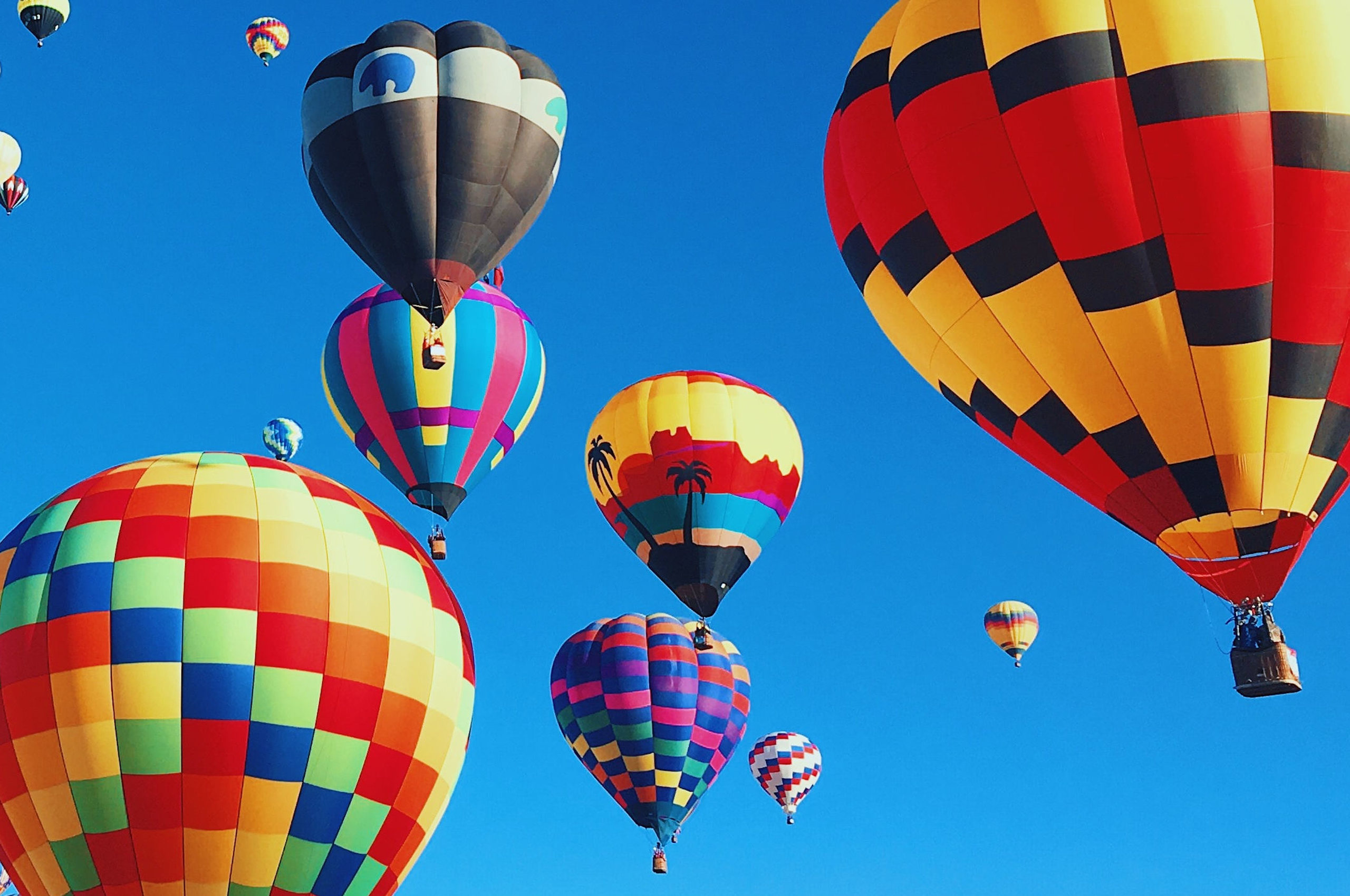 Colourful hot air balloons floating up against a blue sky