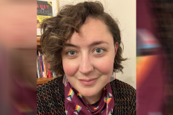 An image of a person wearing a Progessive LQBTQ scarf with curly hair and rainbow earrings