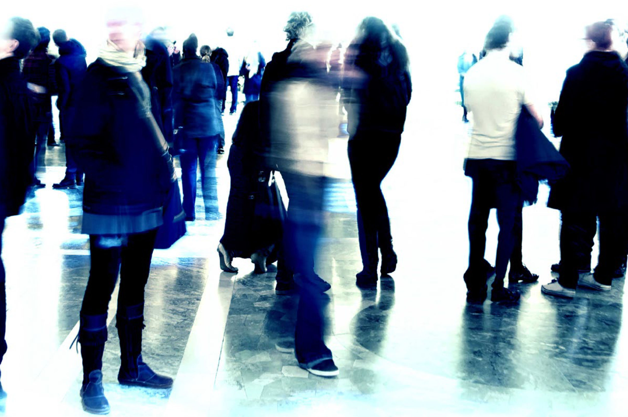 Over-exposed, blurred image of people standing and walking in a large public area