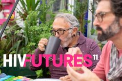 Two older men having breakfast at a garden table, one with glasses and a stretcher piercing drinking coffee, and one with glasses eating a muffin