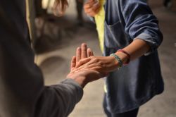 Two people are reaching out their arms and taking hold of each other's hand in a display of support