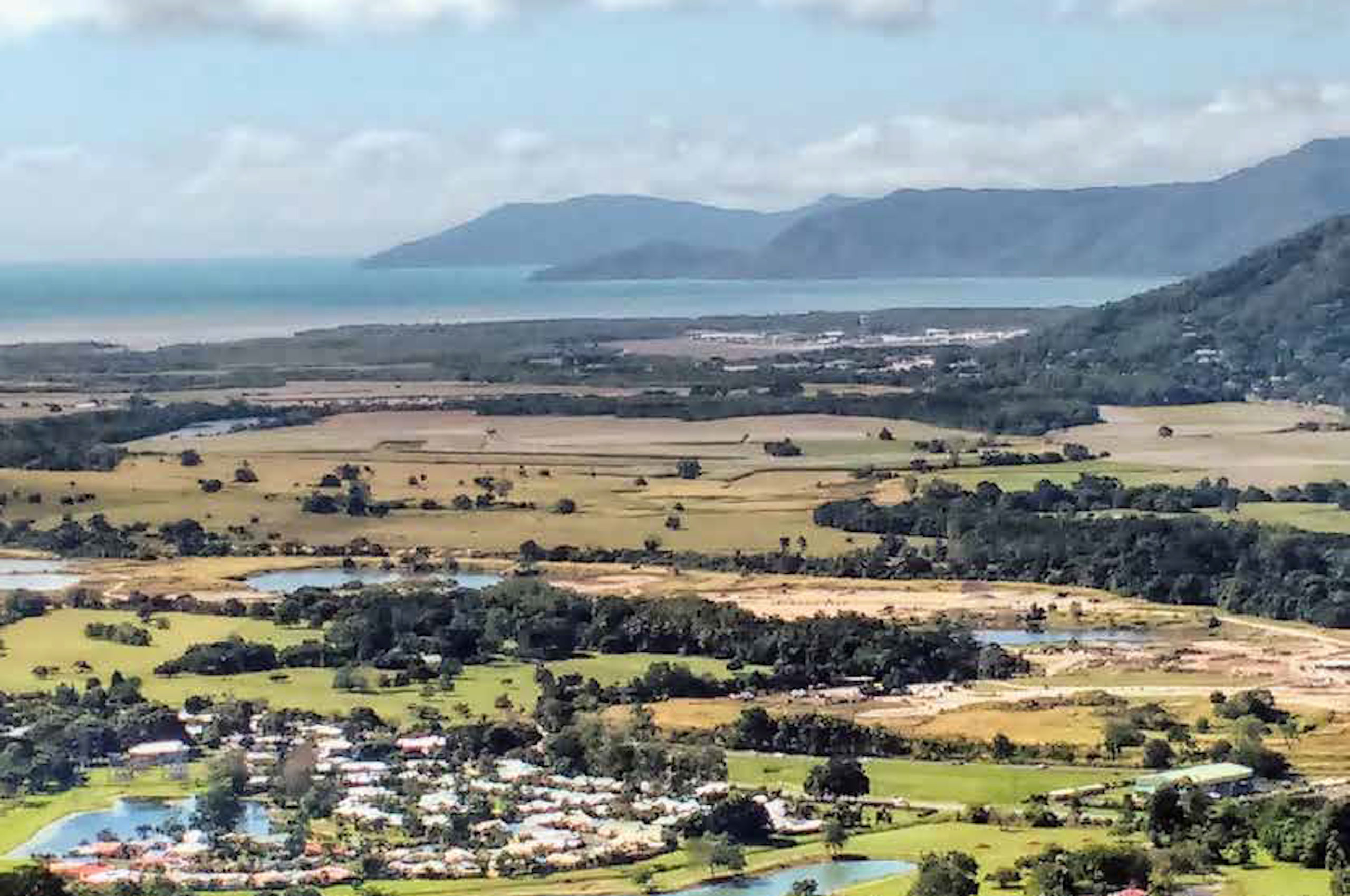 Aerial photograph of fields, trees, the sea and a beach with rocky headlands