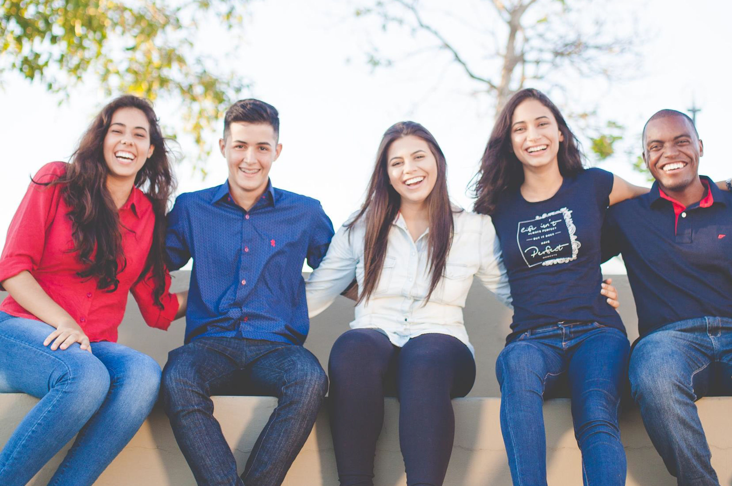 Five young people sitting on a bench, smilin