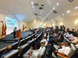 A man standing behind a podium in a classroom full of people