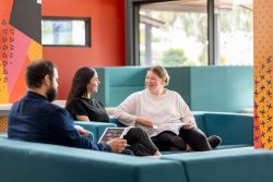 Image of students sitting on a couch talking to each other.