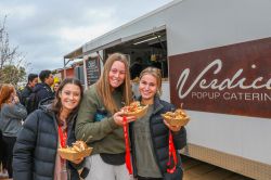 three female teenagers holding food outside food truck smiling