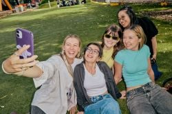 Students smiling and taking a group selfie on La Trobe University campus.