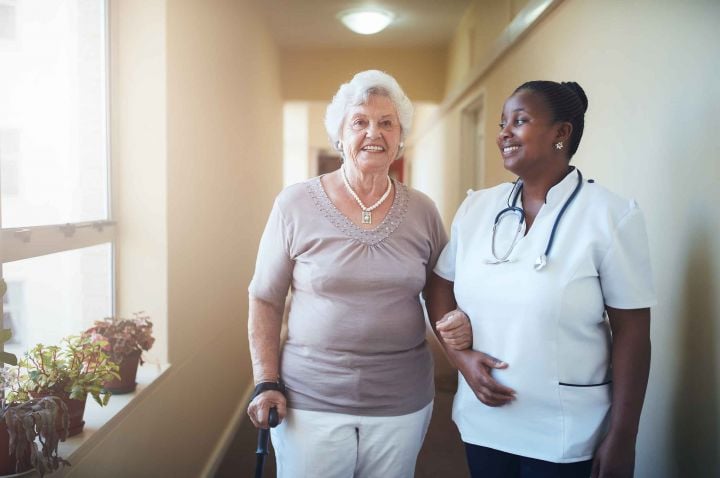 Old woman being supported by a medical practitioner.
