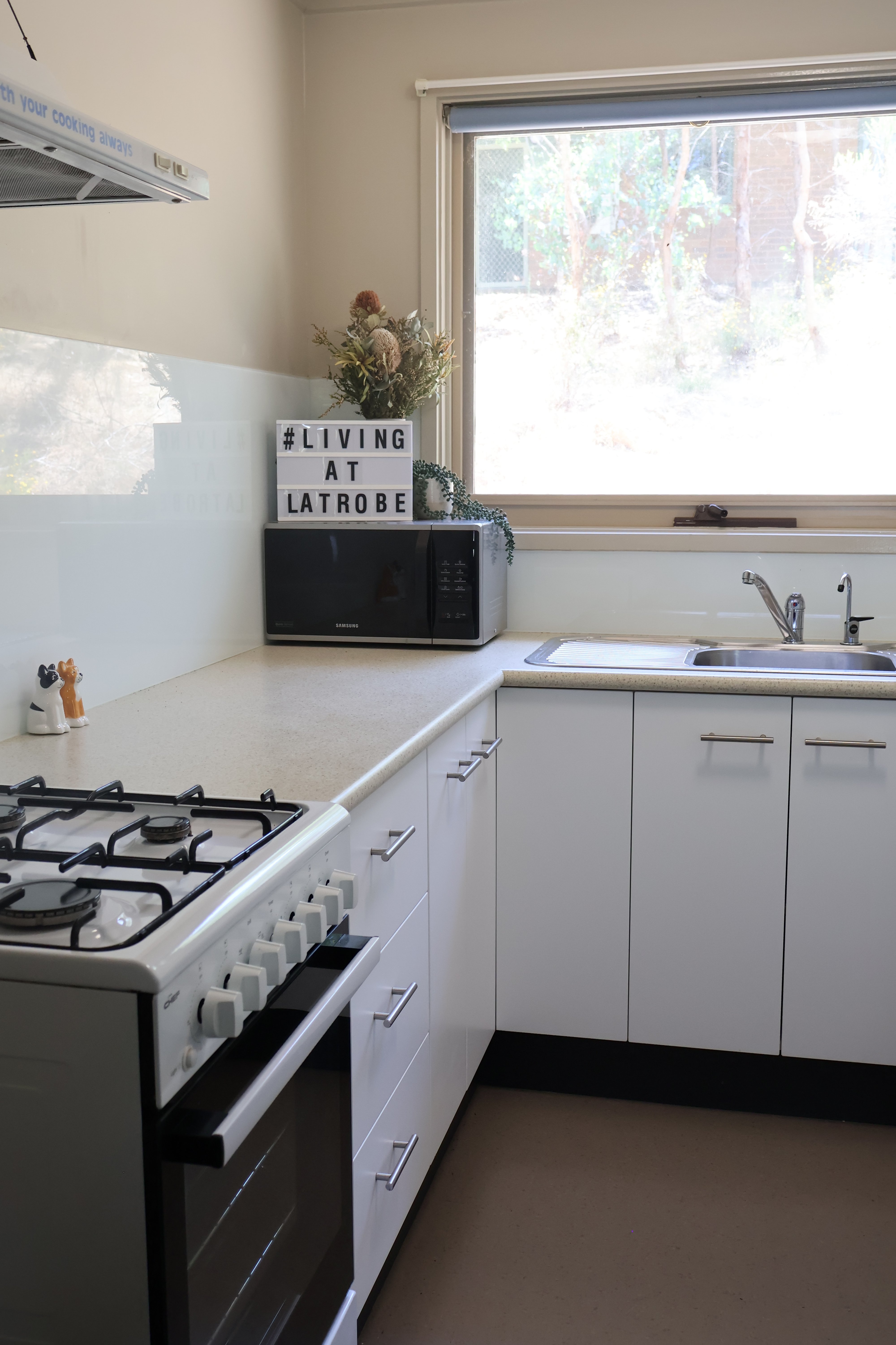 Gas stove top and kitchen bench with microwave, showing kitchen of Terraces in Bendigo.