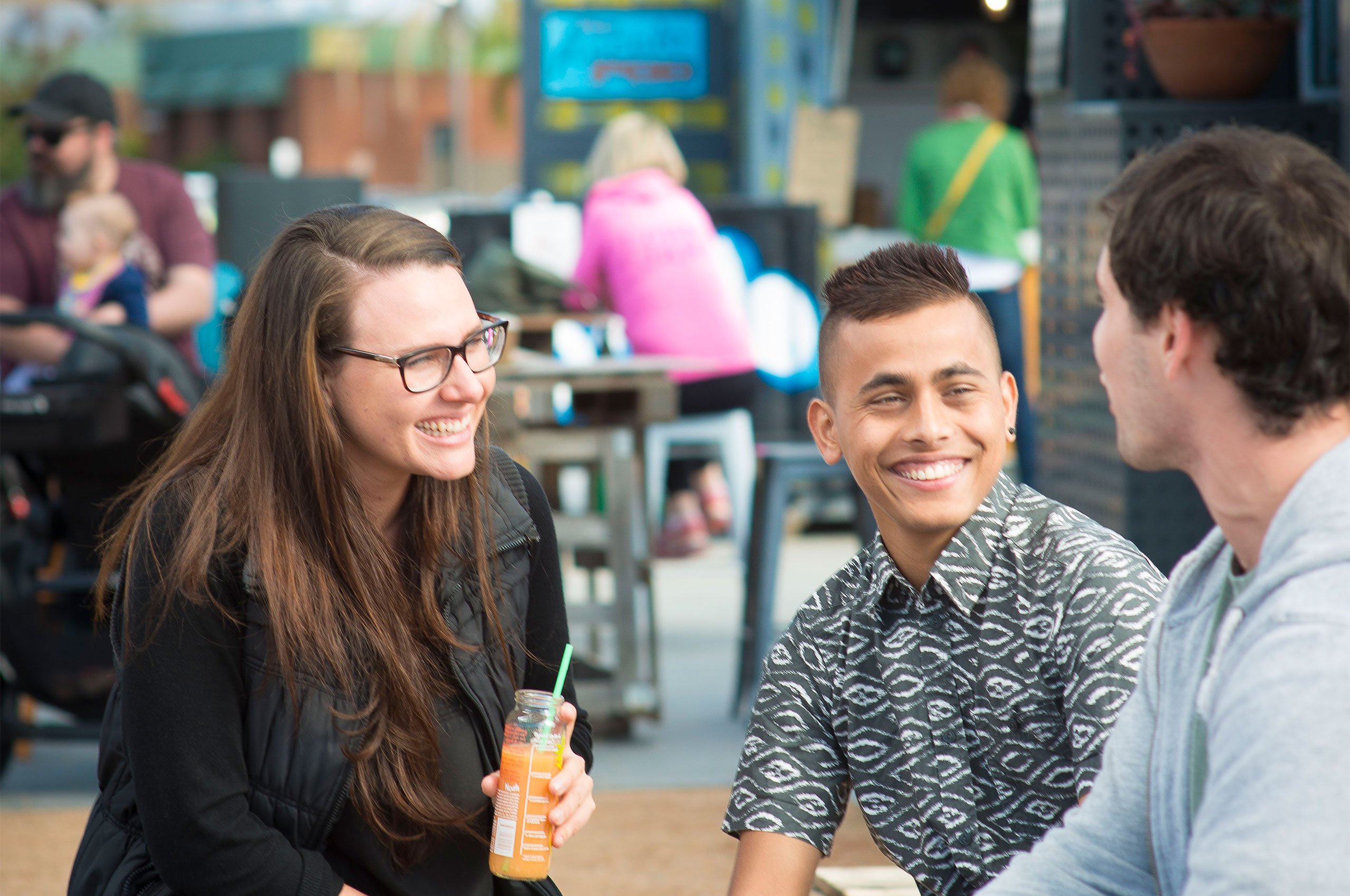 Woman and two men socialising in outdoor seating area