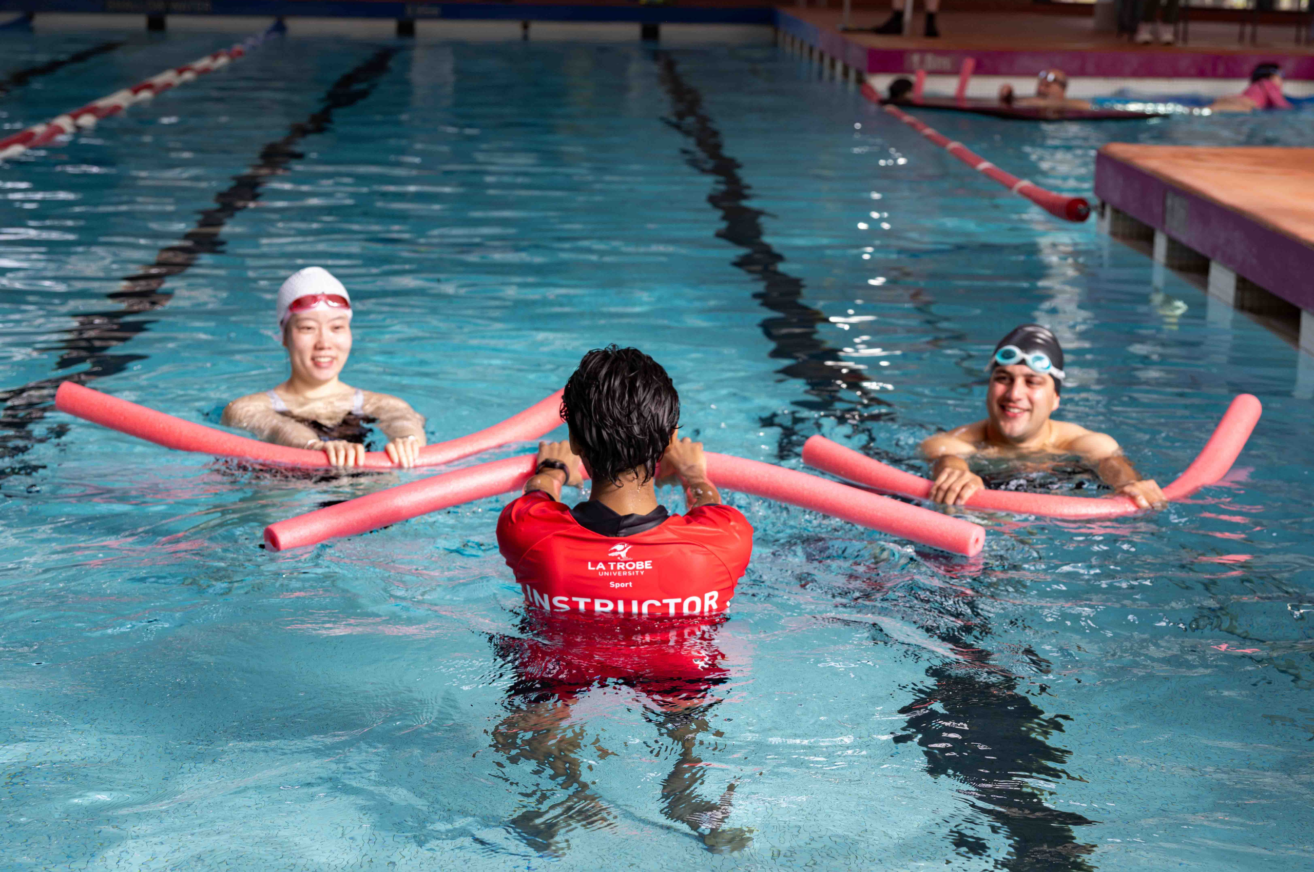 Swim School Adult Lessons - two adults and one instructor swimming in a pool