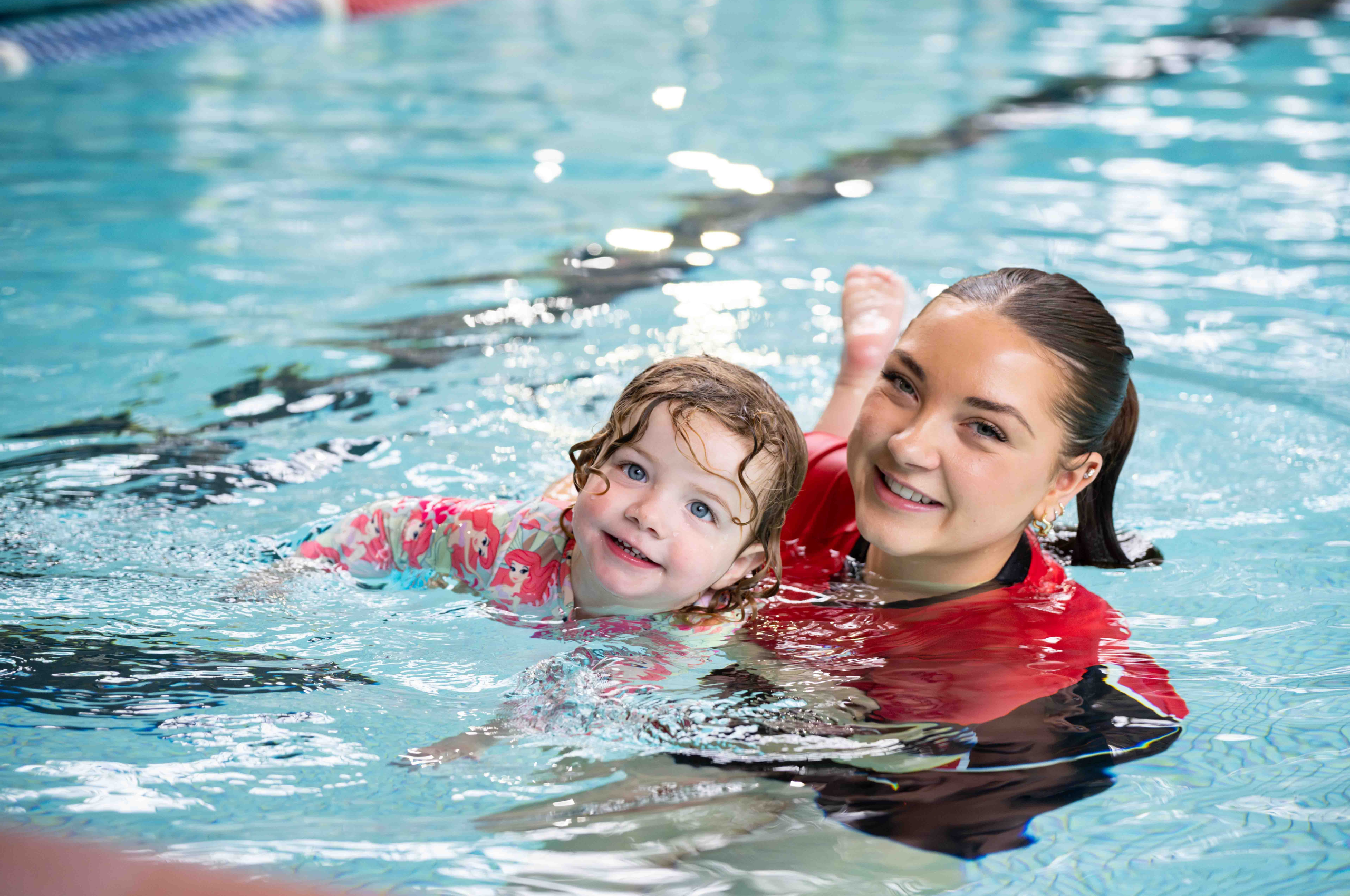 Instructor holding kid in pool