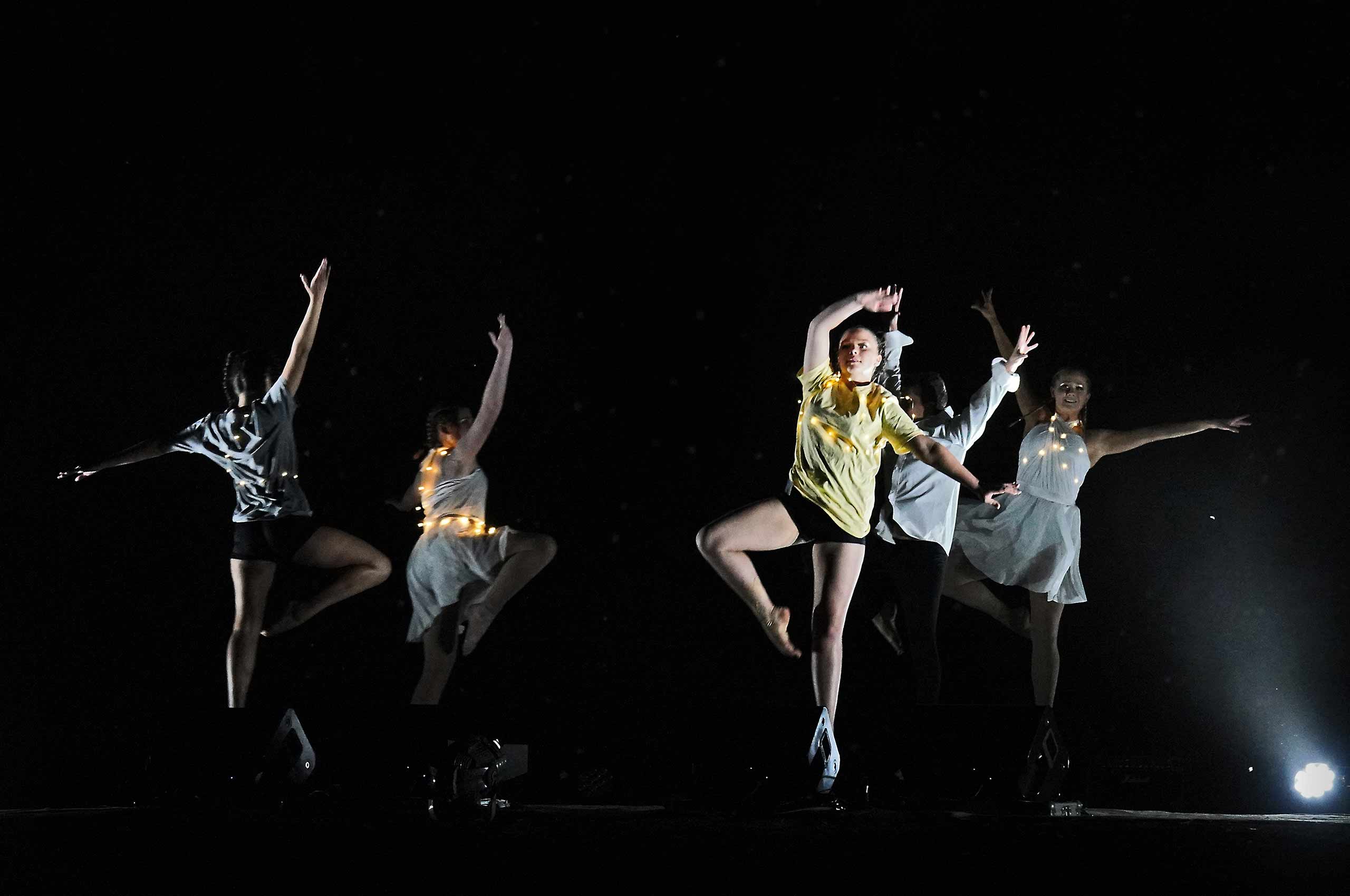 Five people dancing outside at night.