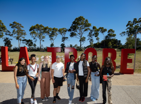 Group of students in front of the large LA TROBE letters on the Bendigo Campus. 