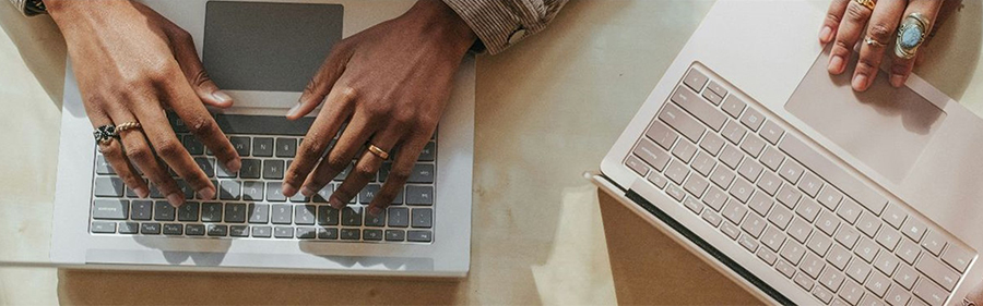 Top-down view of two people's hands resting on their laptops