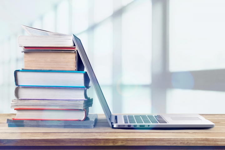 Stack of books, open laptop