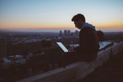 Person using a laptop with a view of a city skyline