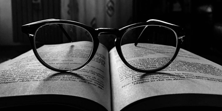 A pair of glasses resting on an opened book