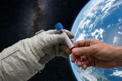 Two hands exchanging a test tube of red liquid. One had is in a space suit, the other is a bare hand. The background has both space and the earth from space.