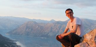 alex exploring overseas with La Trobe, sitting on rocks overlooking a mountain view