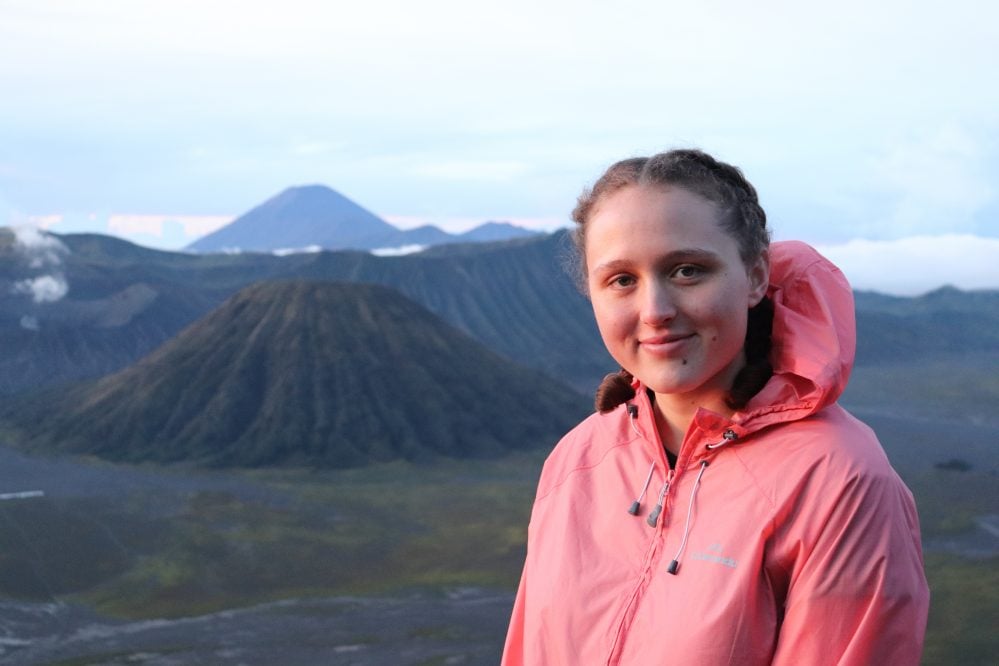 Person standing with volcanoes in the distance.