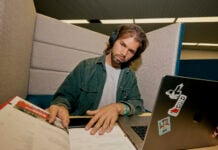 A student studying in the library with their laptop and notebooks