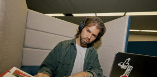 A student studying in the library with their laptop and notebooks