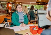 A student sitting with a notebook talking to ASK La Trobe in the Library