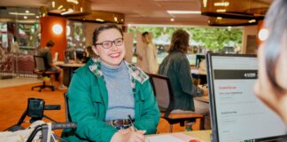 A student sitting with a notebook talking to ASK La Trobe in the Library
