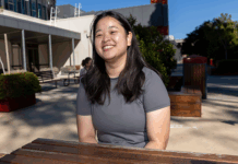 Student wearing a grey t shirt sitting across the table smiling at the Bendigo campus