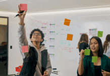 Students in class sticking post-it notes on the wall.