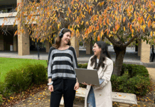 Two students smiling with a new laptop and headphones