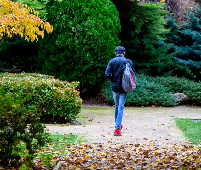The back of a student walking away in the international garden