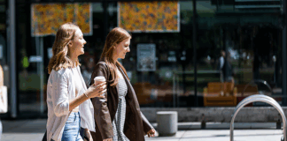 Two students walking and one is holding a coffee