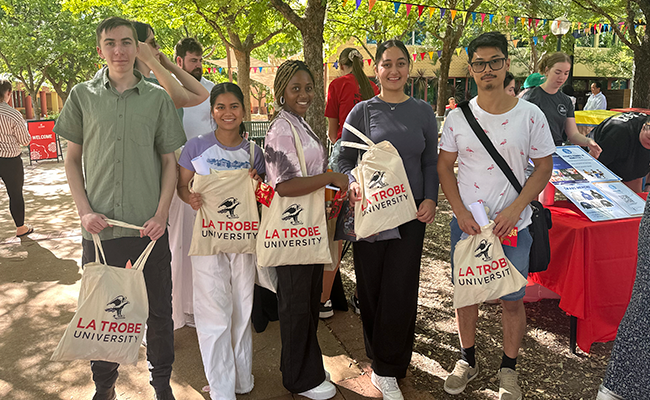 AW O Week image_WordPress Article (650 x 400) Students posing for a photo at O Week holding La Trobe branded tote bags