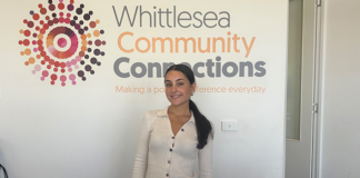 La Trobe student Emily standing in front of the Whittlesea Community Connections sign