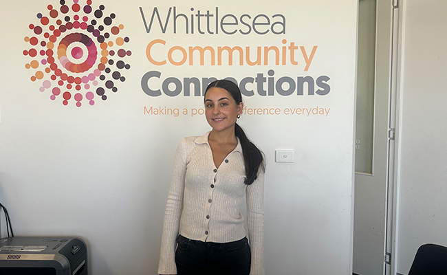 La Trobe student Emily standing in front of the Whittlesea Community Connections sign