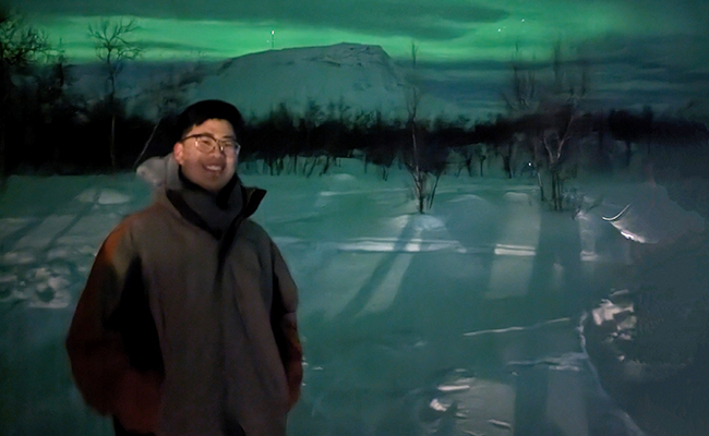 Student Jack in front of the northern lights in Finland