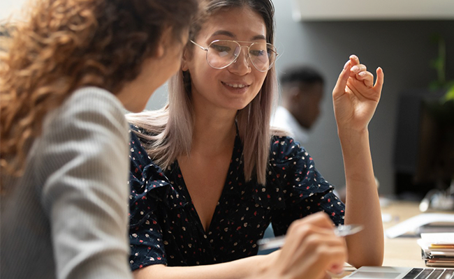 Two students looking at computer and having a conversation