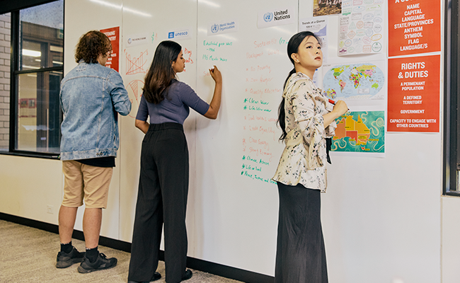 Students working on a group assignment, drawing on board