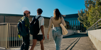 Three students walking across the bridge on campus