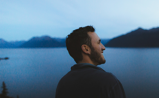 A young man smiling and looking out in the distance