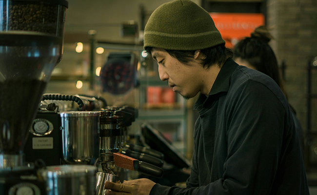 A barista making coffee wearing a beanie