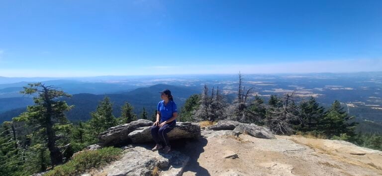 A woman looking out at a beautiful view from the top of a hike.