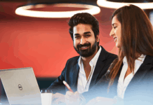 Two students in business attire working together at a laptop.