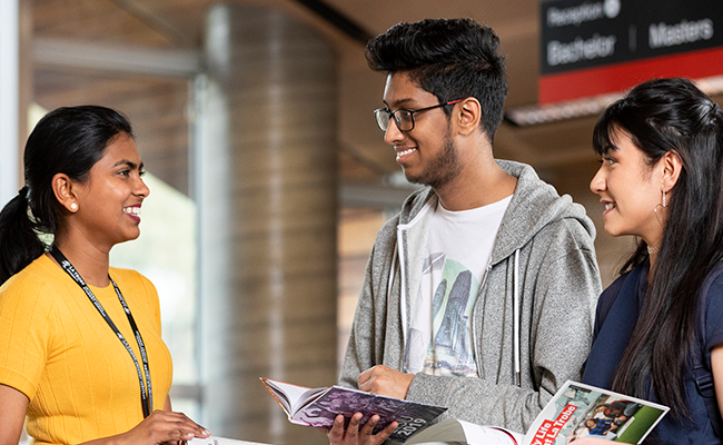 Three students talking and reading books