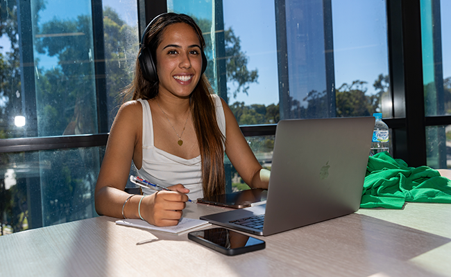 Placements_Double Block (310 x 200) – ROUNDED_v2 Student wearing headphones working on laptop